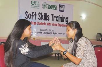 Photo: Soft-Skills training conducted by RBI, Philippines - two visually impaired female students sitting across from each other with fingers touching