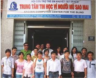 Photo: a group of staff and trainees stood in front of the Sao Mai Computer Center for Blind