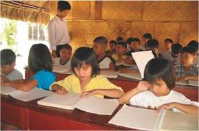 Photo: a classroom with young students sitting in rows reading braille books