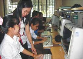 Photo: A female teacher instructing students to use computer 