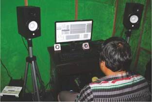 Photo: a visually impaired person sitting in his audio lab working on an audio file