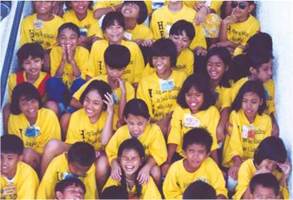 photo: a group of smiling students wearing yellow top sitting in a stairways